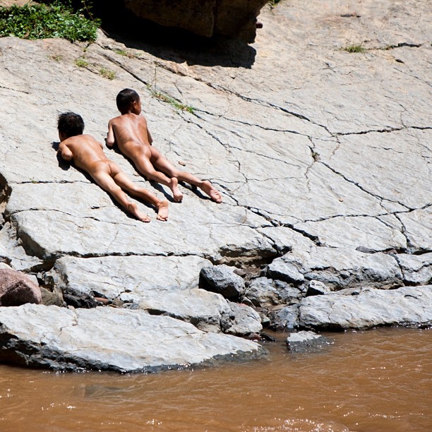 two  men sitting on some rocks in the water