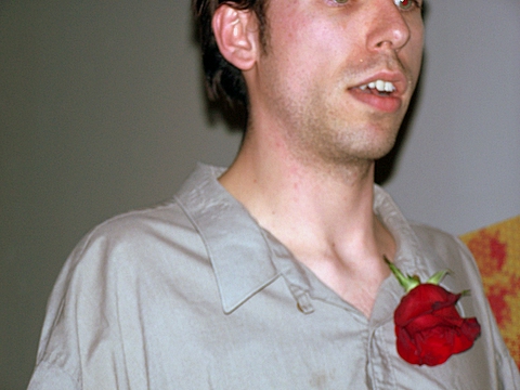 a man is wearing a rose flower on his lap