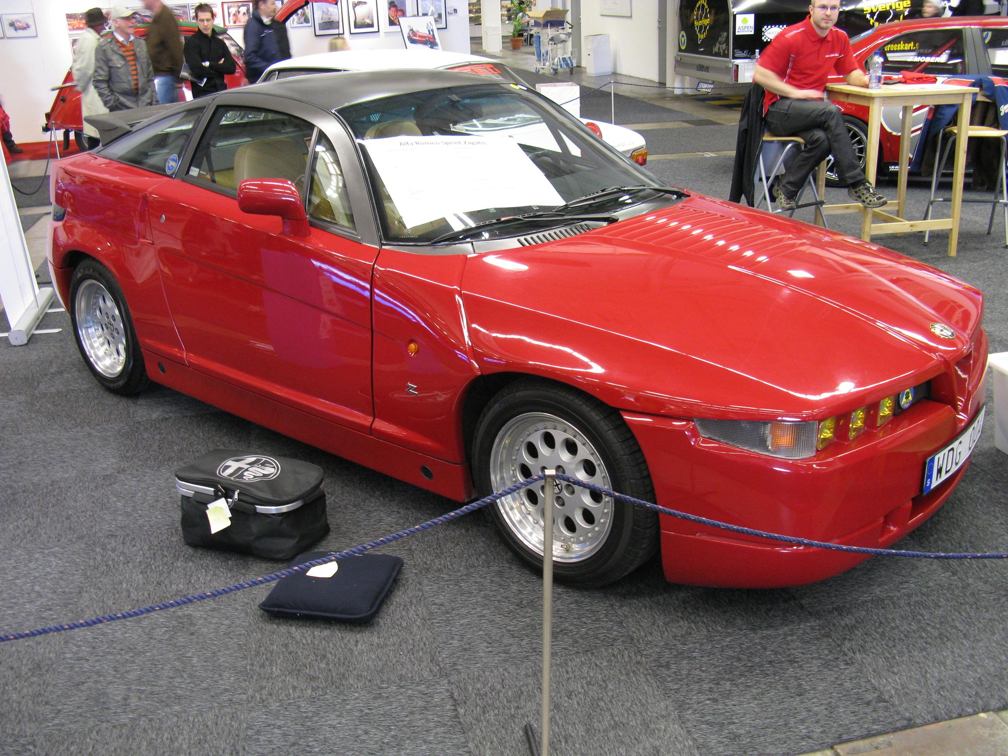 red sports car with white interior parked near a table