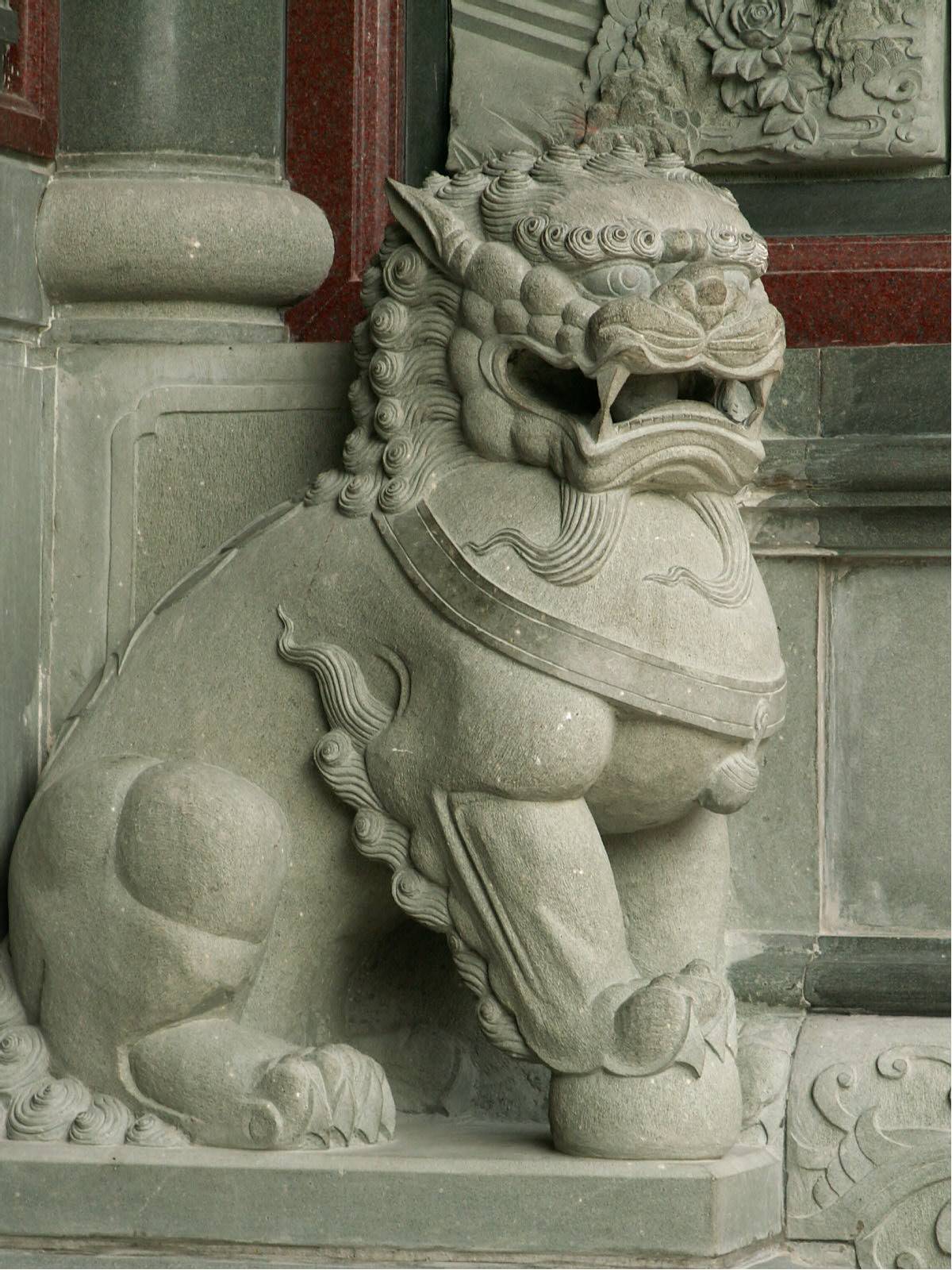 an old stone lion statue is next to a window