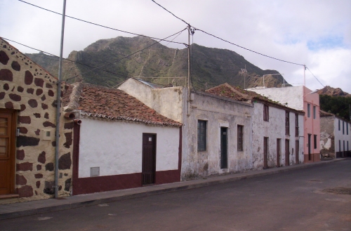 old buildings on the road with a mountain in the background