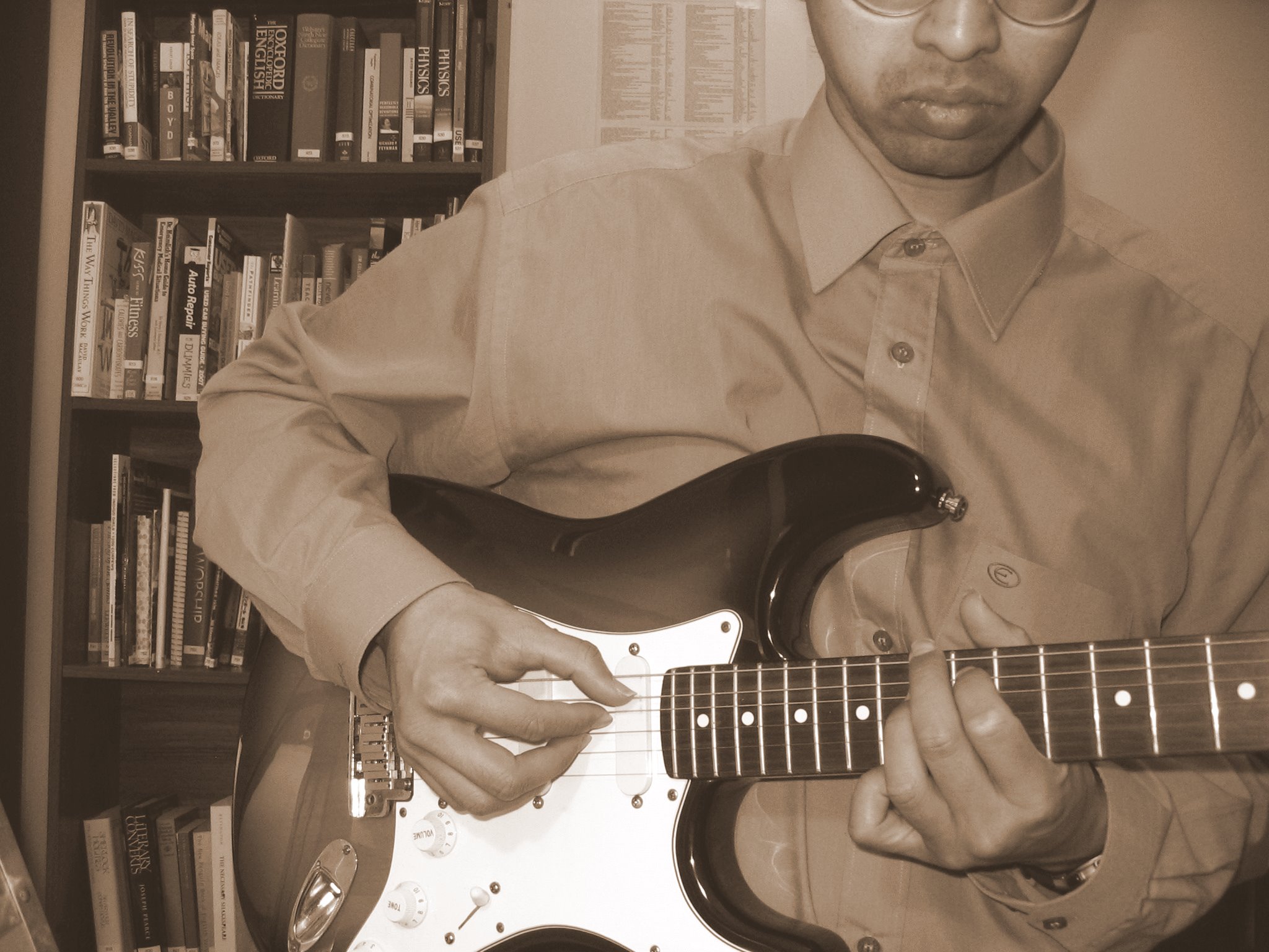 man with glasses and playing an electric guitar