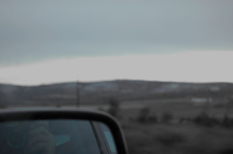 a side view mirror with some mountains in the back