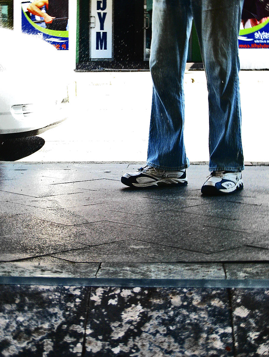a person standing on the sidewalk with their feet on his skateboard