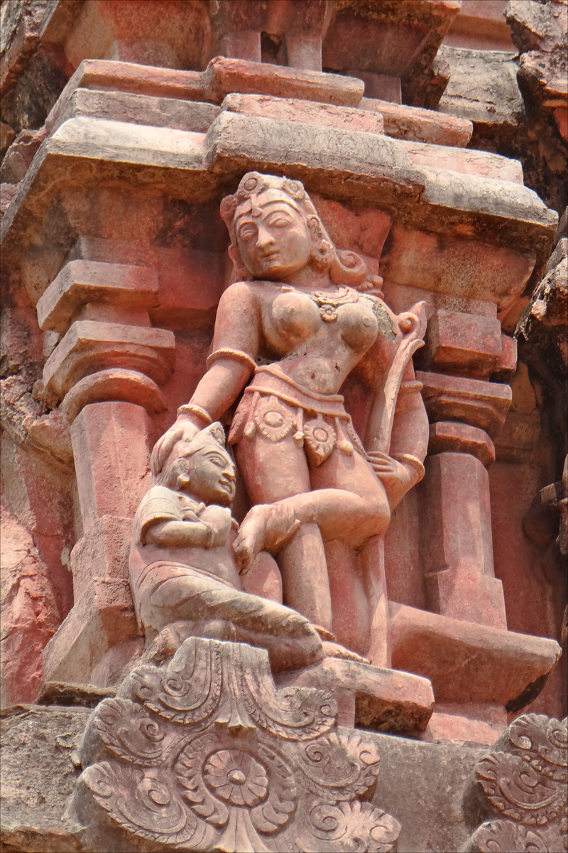 a carved statue of a woman standing next to rocks