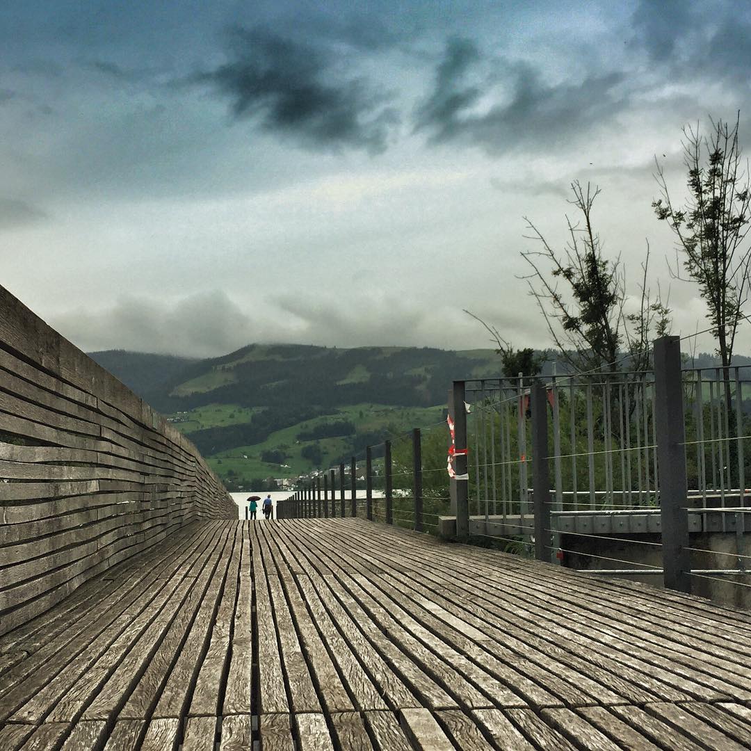 a wooden boardwalk on the shore under a cloudy sky