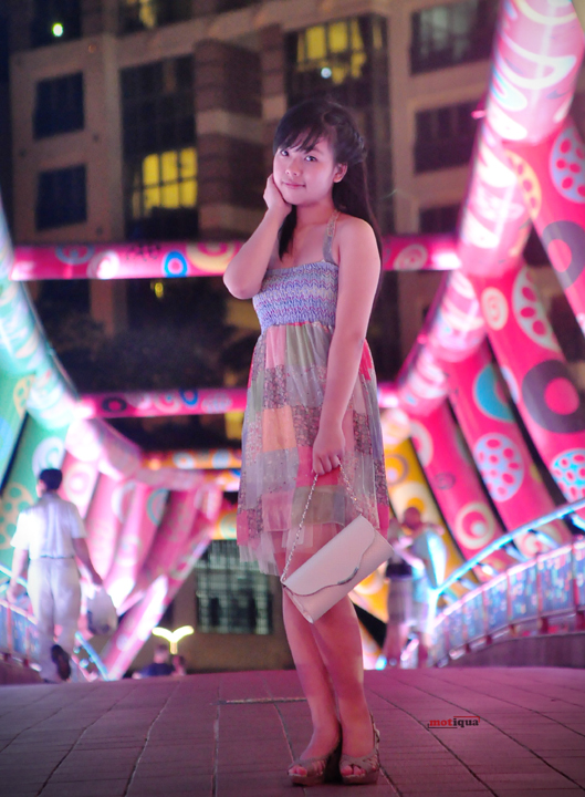 young asian woman standing on sidewalk at night holding her hand on her face