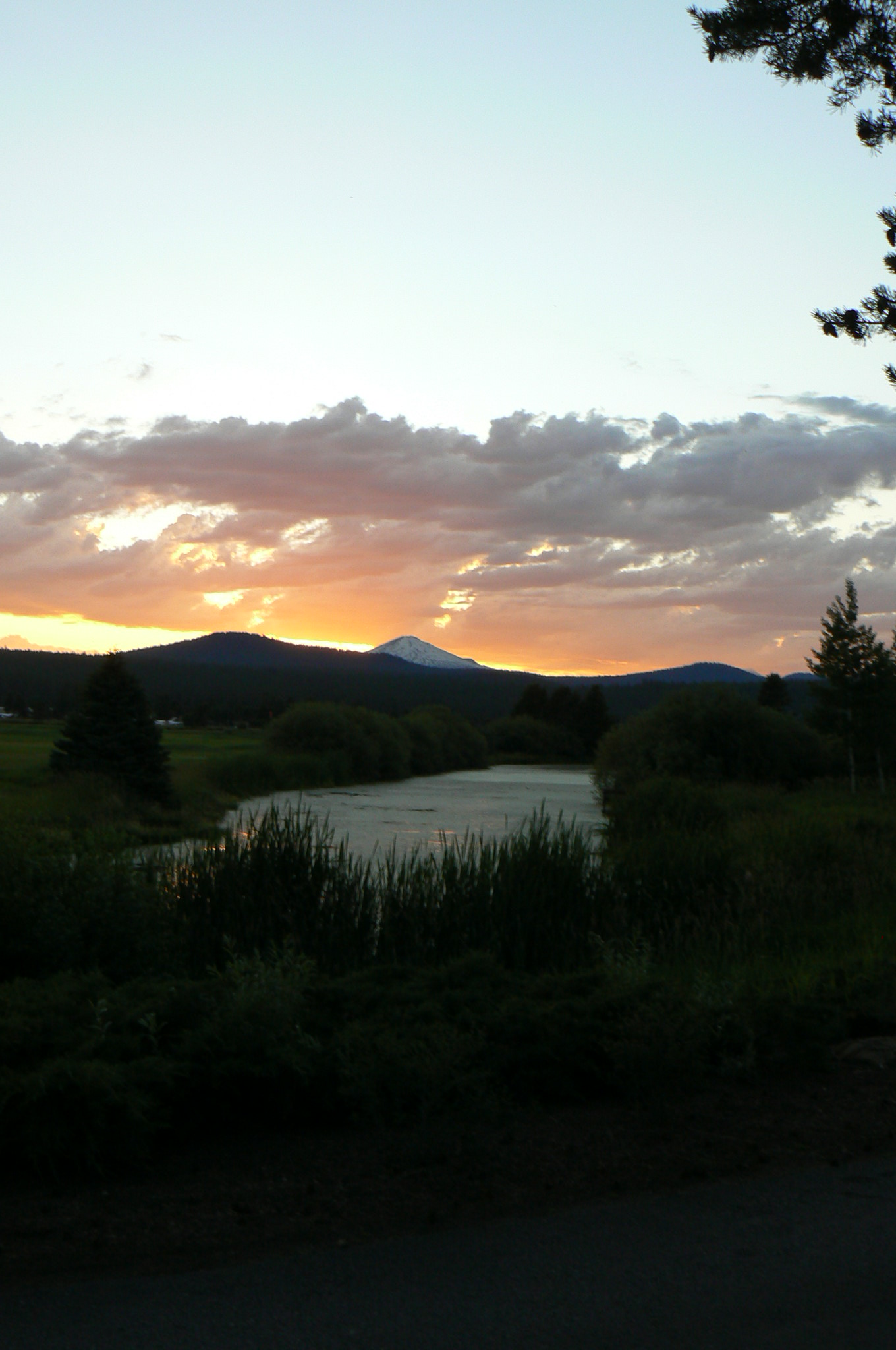 a very bright sunset over a field with a lake