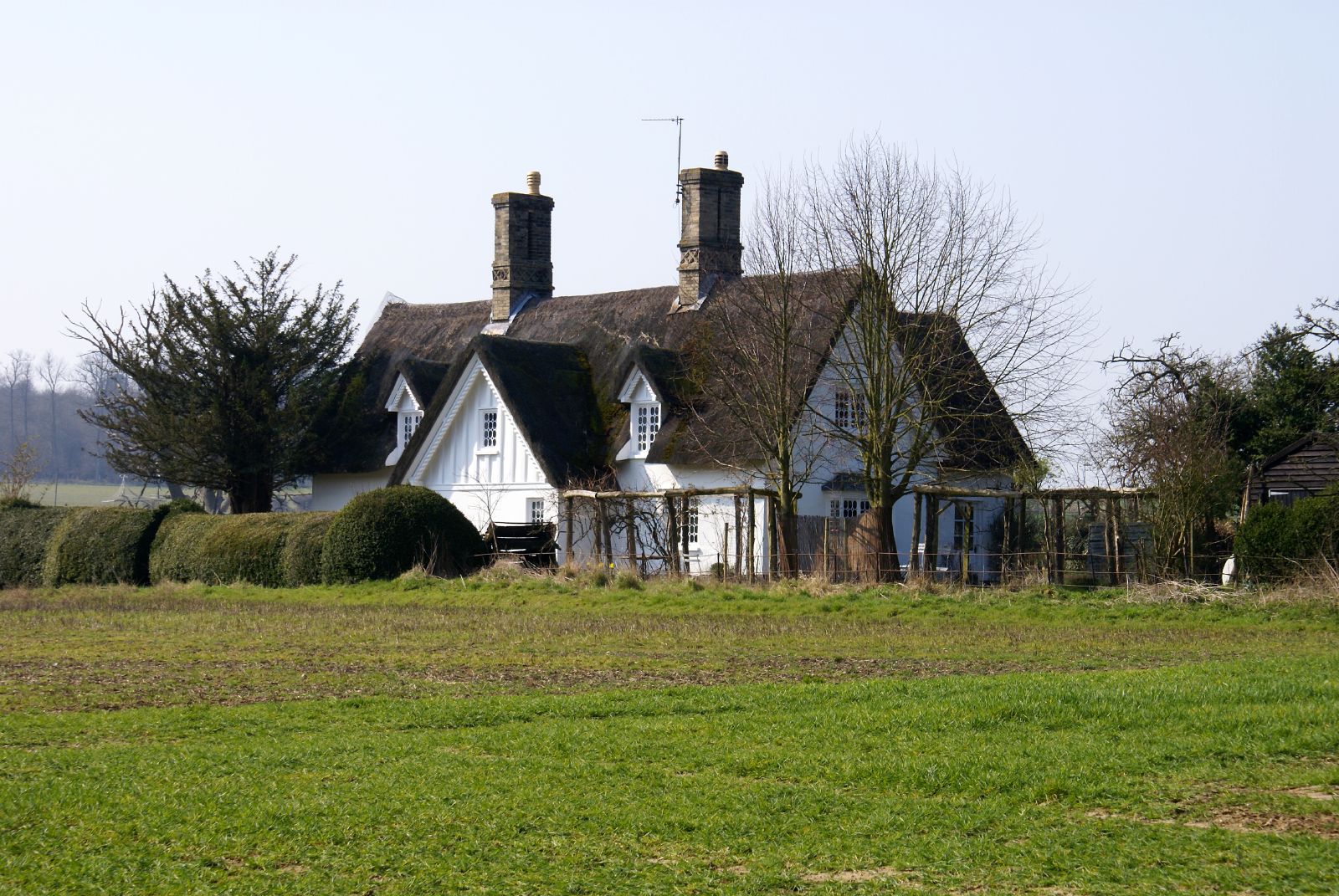 an old white farm house is situated near some trees