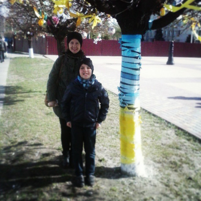 two people standing under a tree decorated with yellow streamers