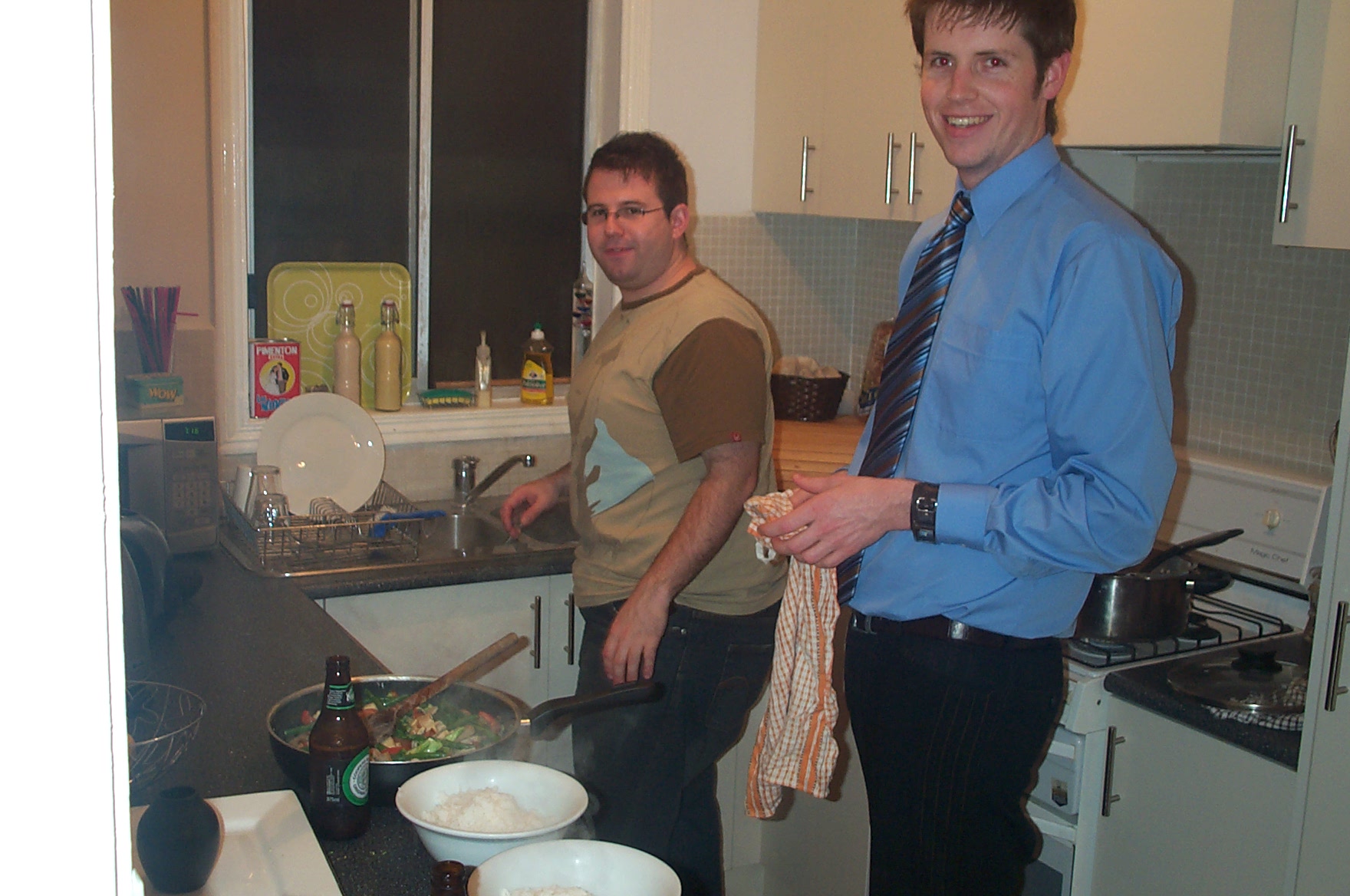 two young men stand in a kitchen preparing food