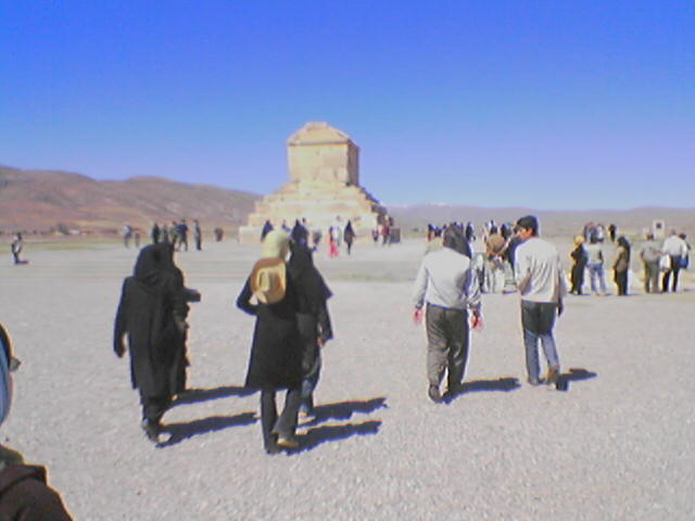 people in black coats standing around at a desert