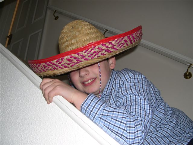 a boy wearing a straw hat while standing on a ledge