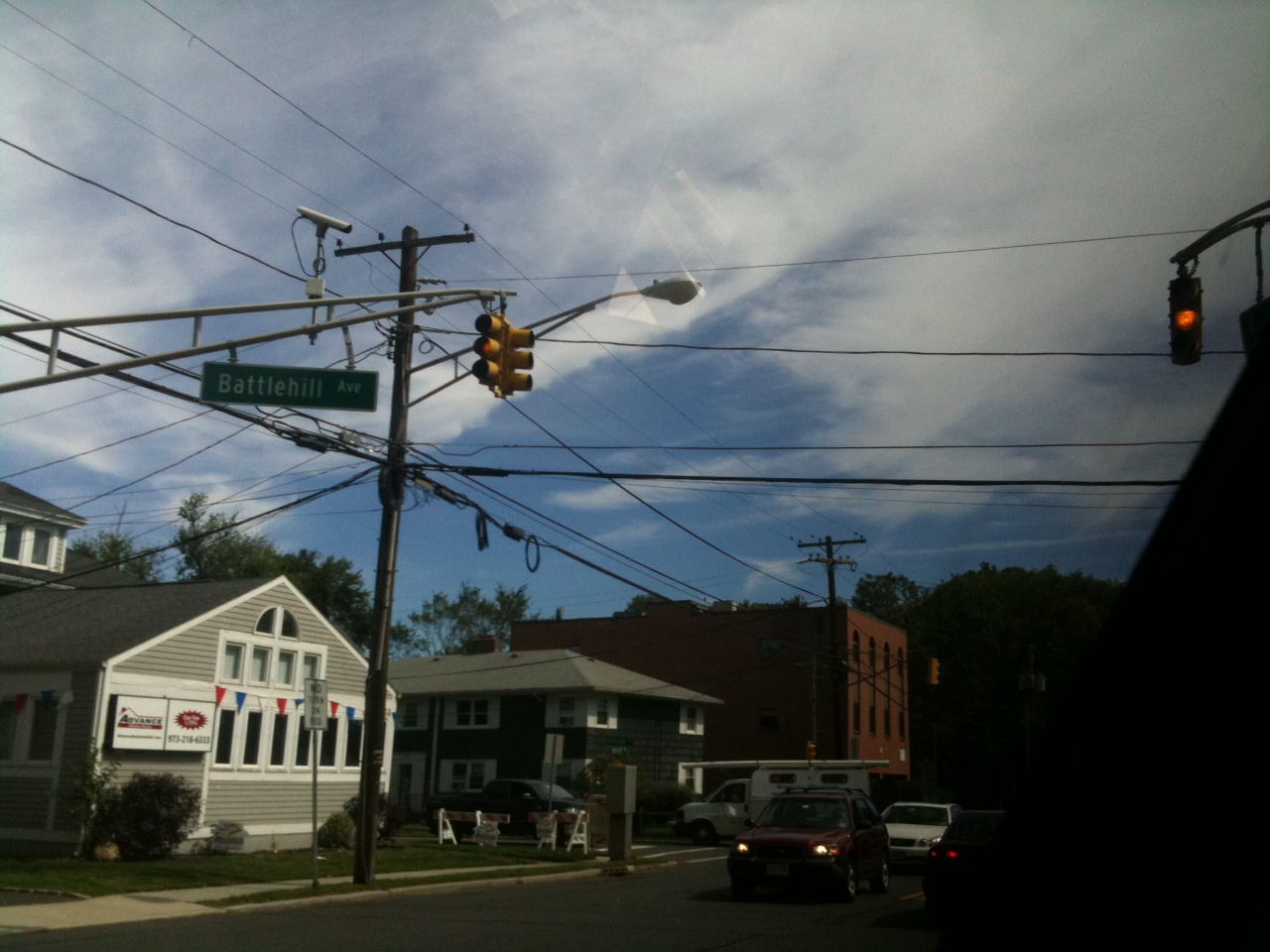 streetlights with street signs on them sitting under wires