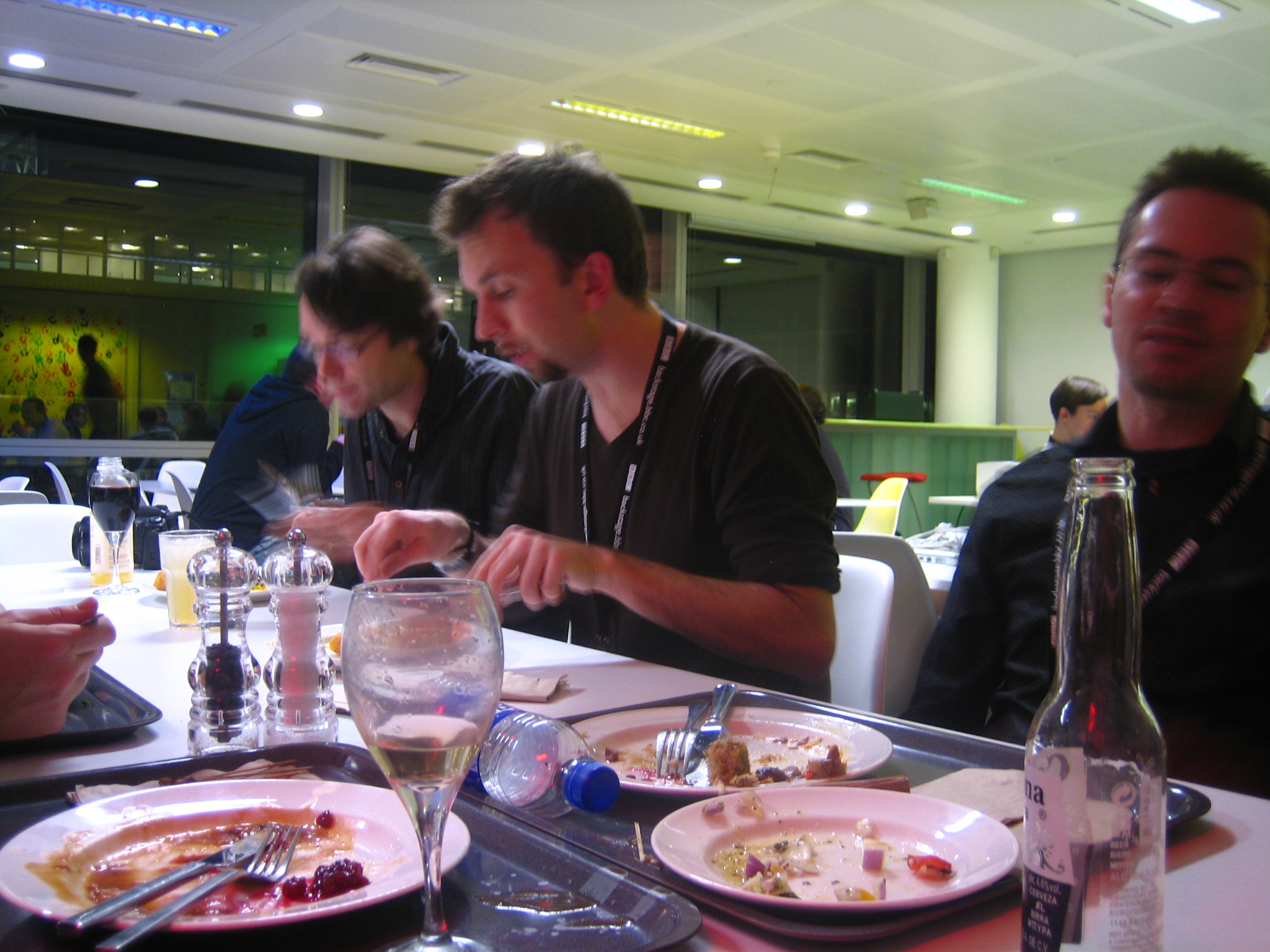 four men sitting at a table eating and drinking wine