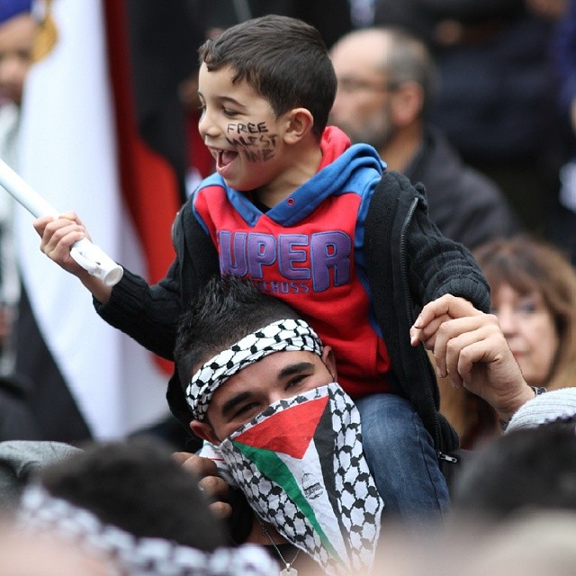 a boy is holding on to his head as they watch the parade