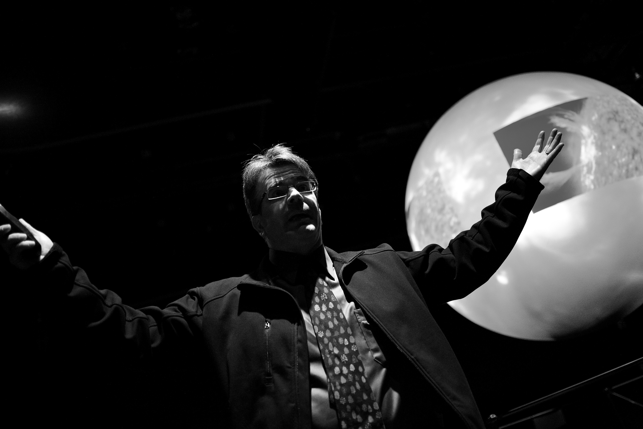 a man giving a presentation on stage with his hands in the air