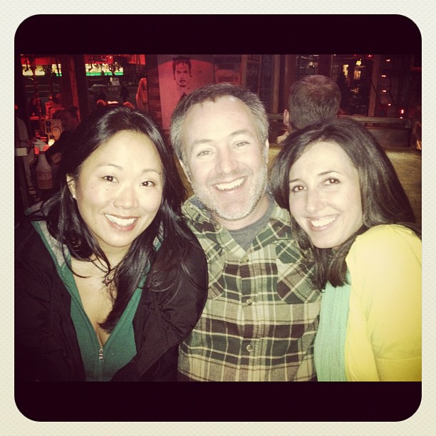 two people and a woman at a bar taking a picture together