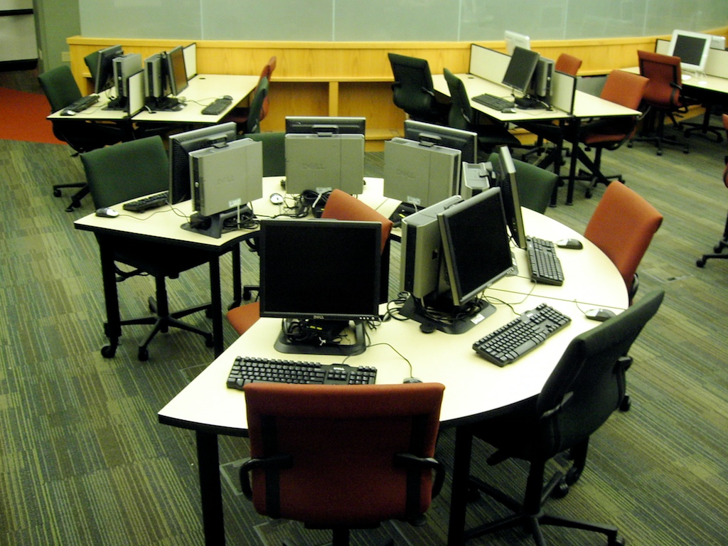 a large meeting room is set up with computer monitors and keyboards