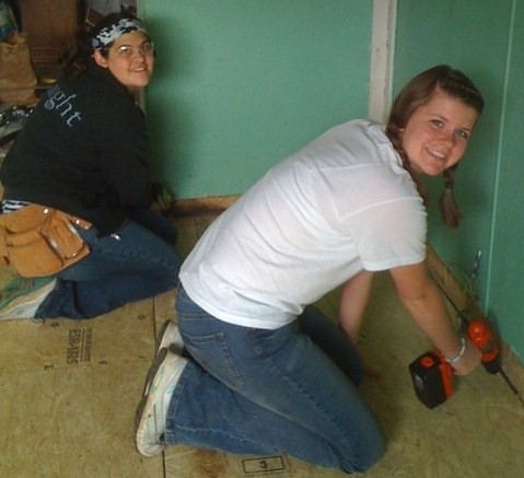 two women are installing a tile floor in a room