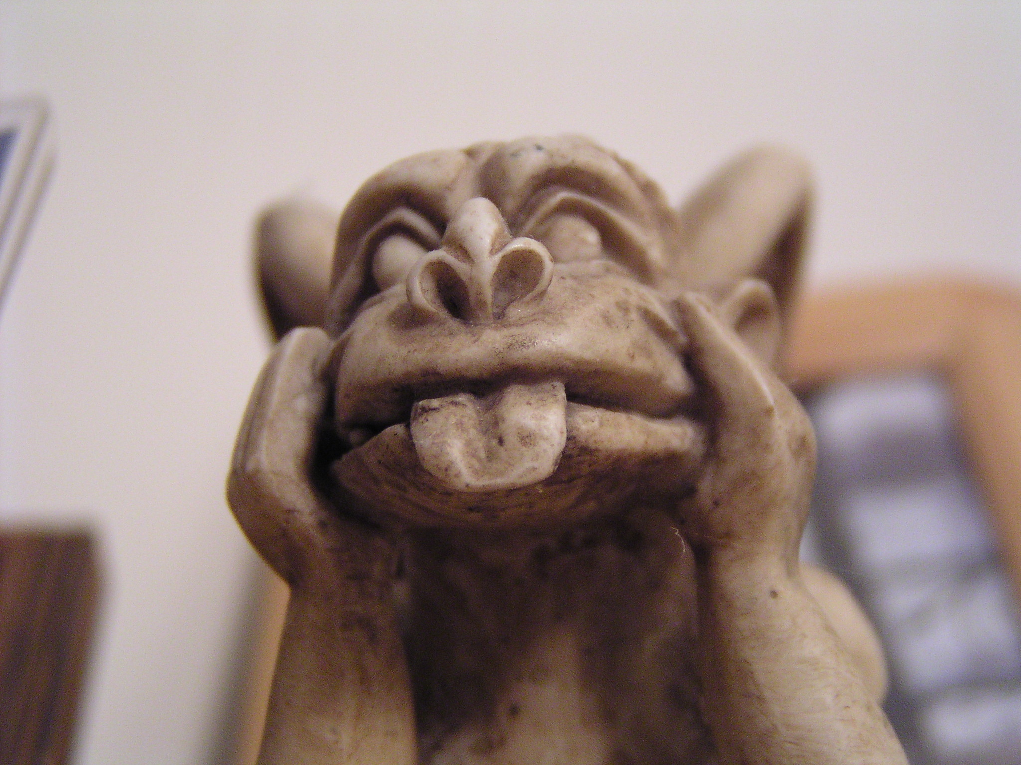 a toy sitting on a desk holding his hands up to his mouth