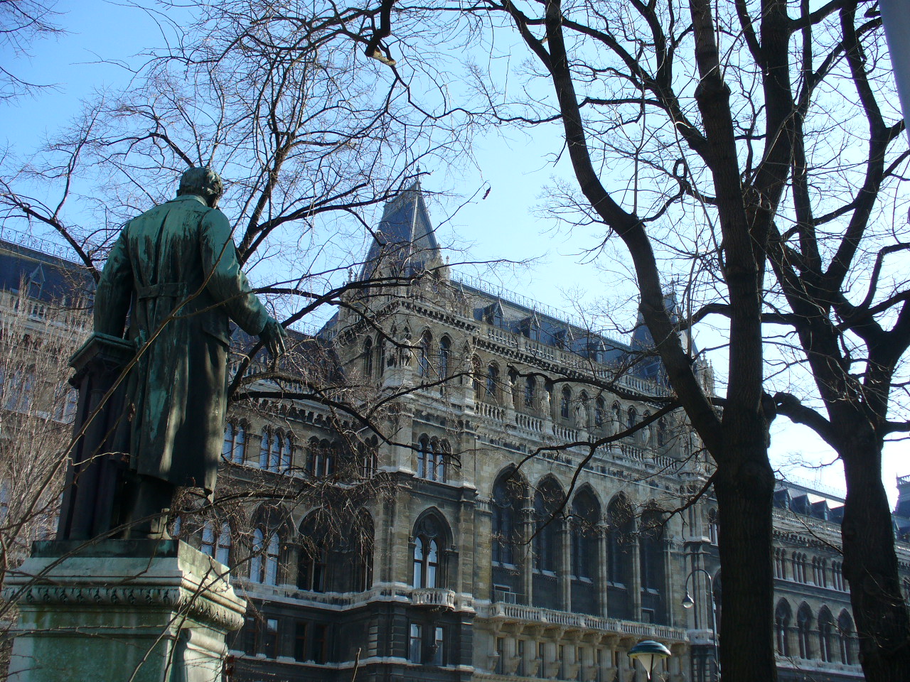 a statue of a man is in the foreground, with old buildings in the background