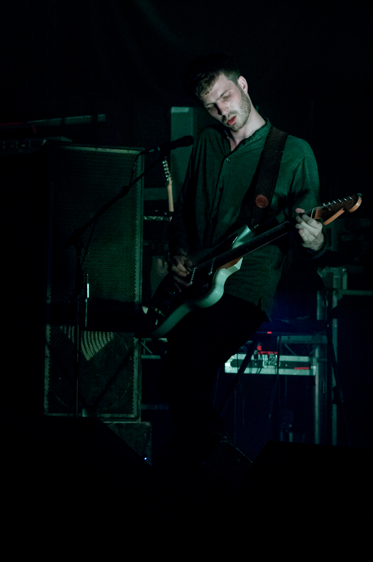 a man standing in the dark with his guitar