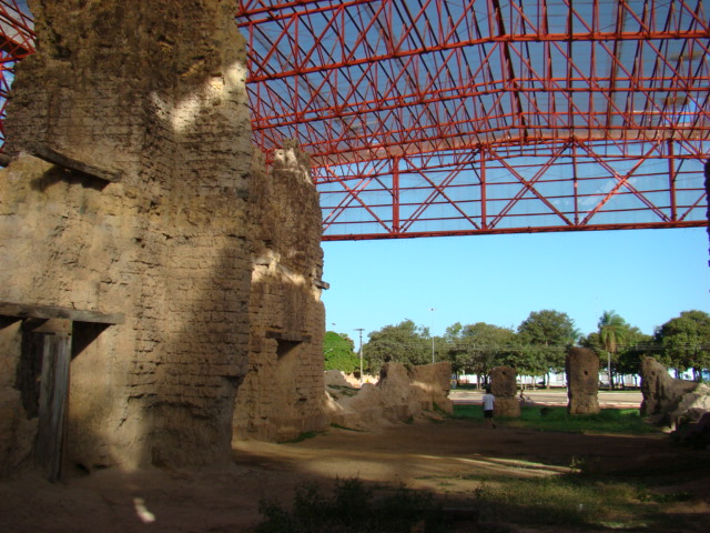 a stone building with a red roof and lots of rocks