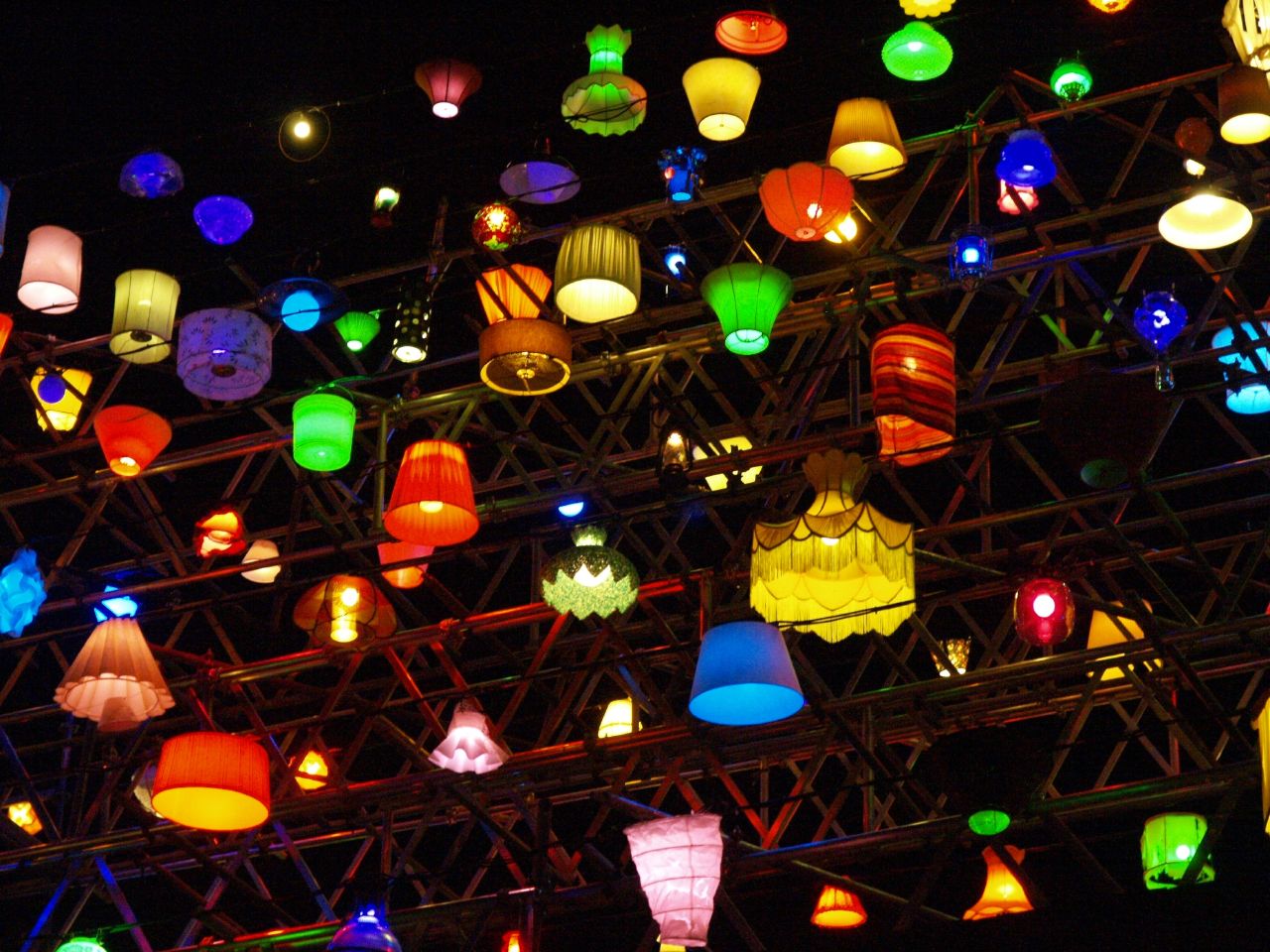 many colorful light bulbs and lights hanging up in a dark room