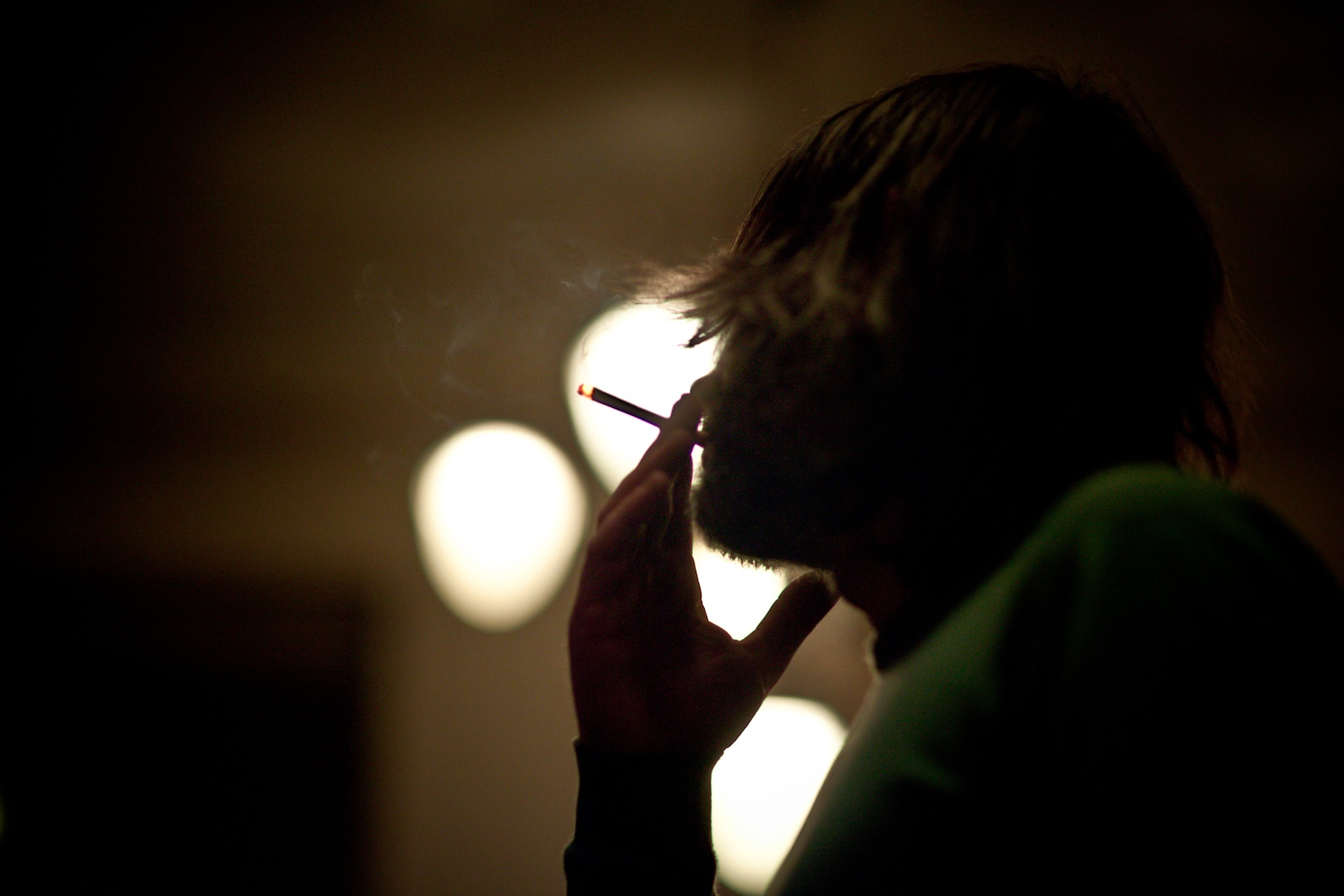 a man smokes his cigarette in a dimly lit room