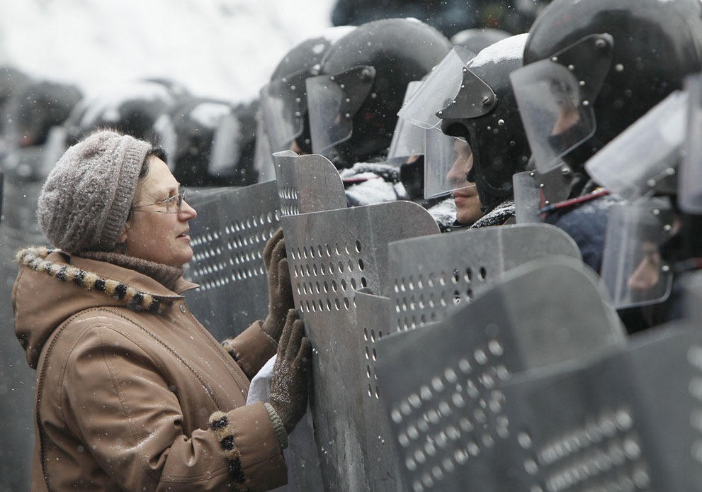 a woman leaning against a wall while surrounded by armor