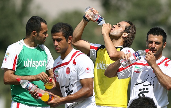 a group of men holding a bottle of water and drinking