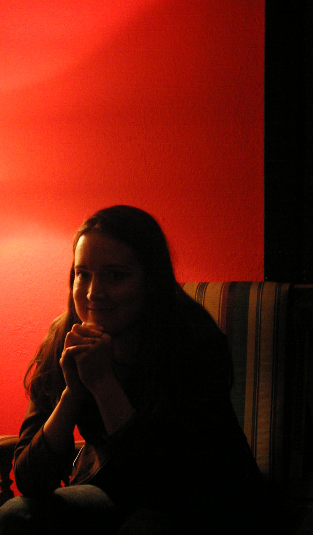 woman sitting in corner of red room with a light on