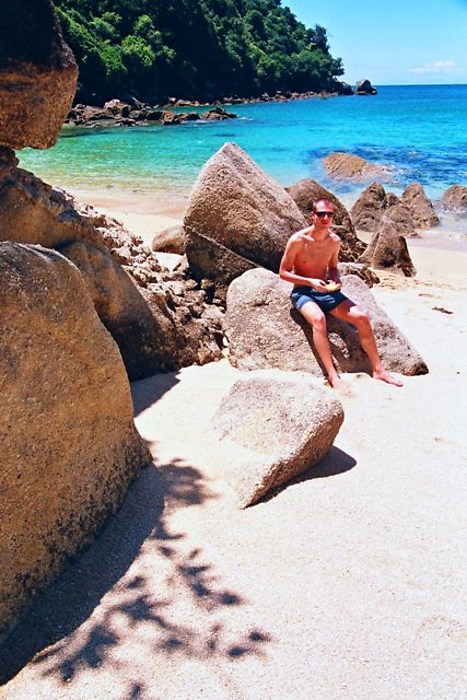 a man sitting on top of rocks near the ocean