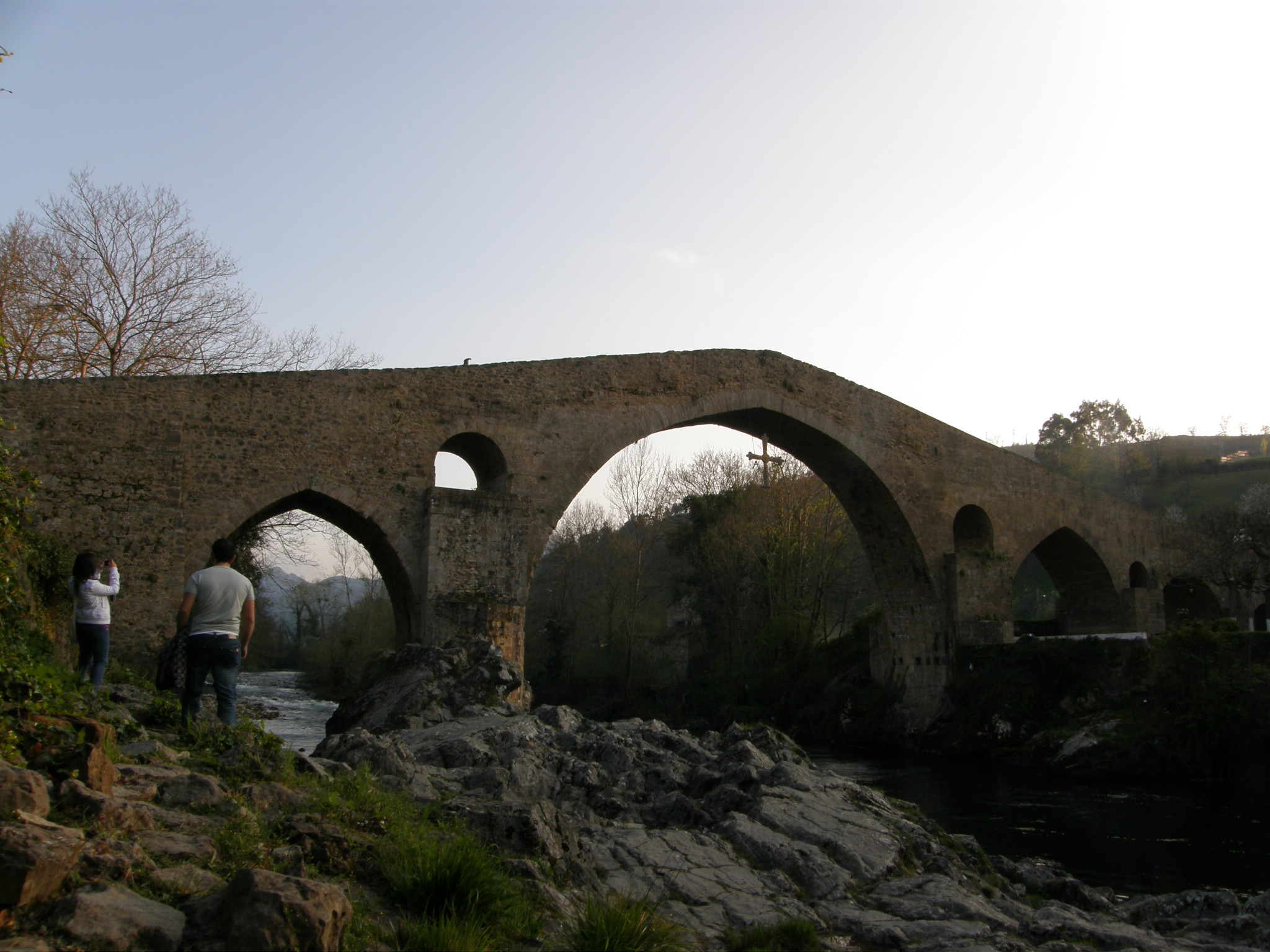 two people are standing on the edge of a small bridge