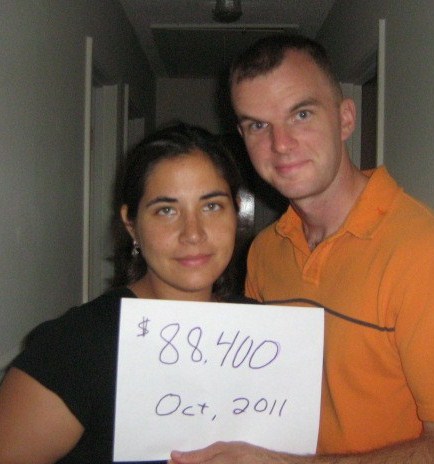 a man and a woman holding up a sign that reads $ 8, 000