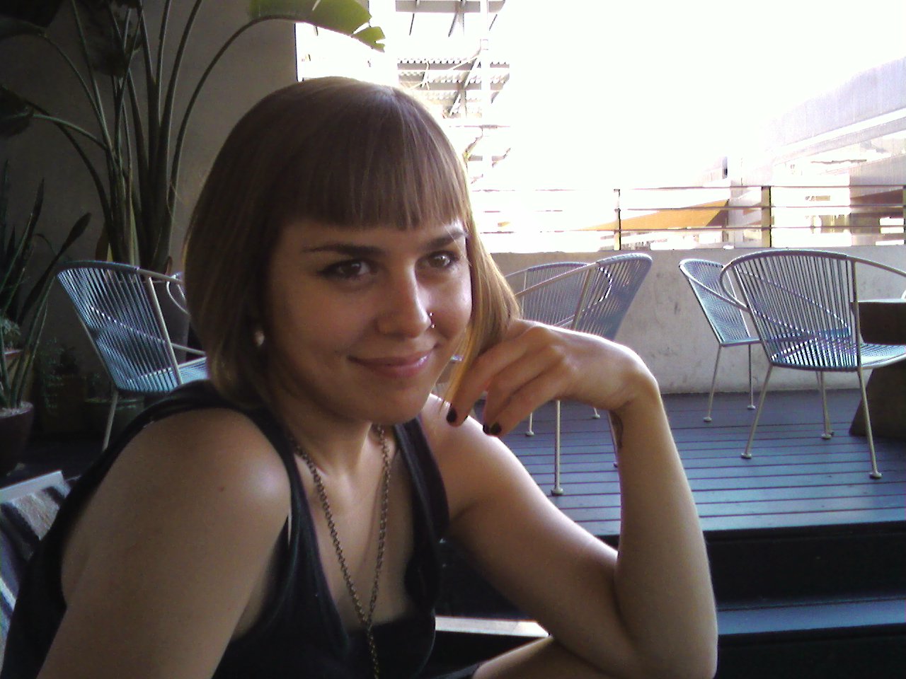 a smiling woman eating food with other chairs and potted plants