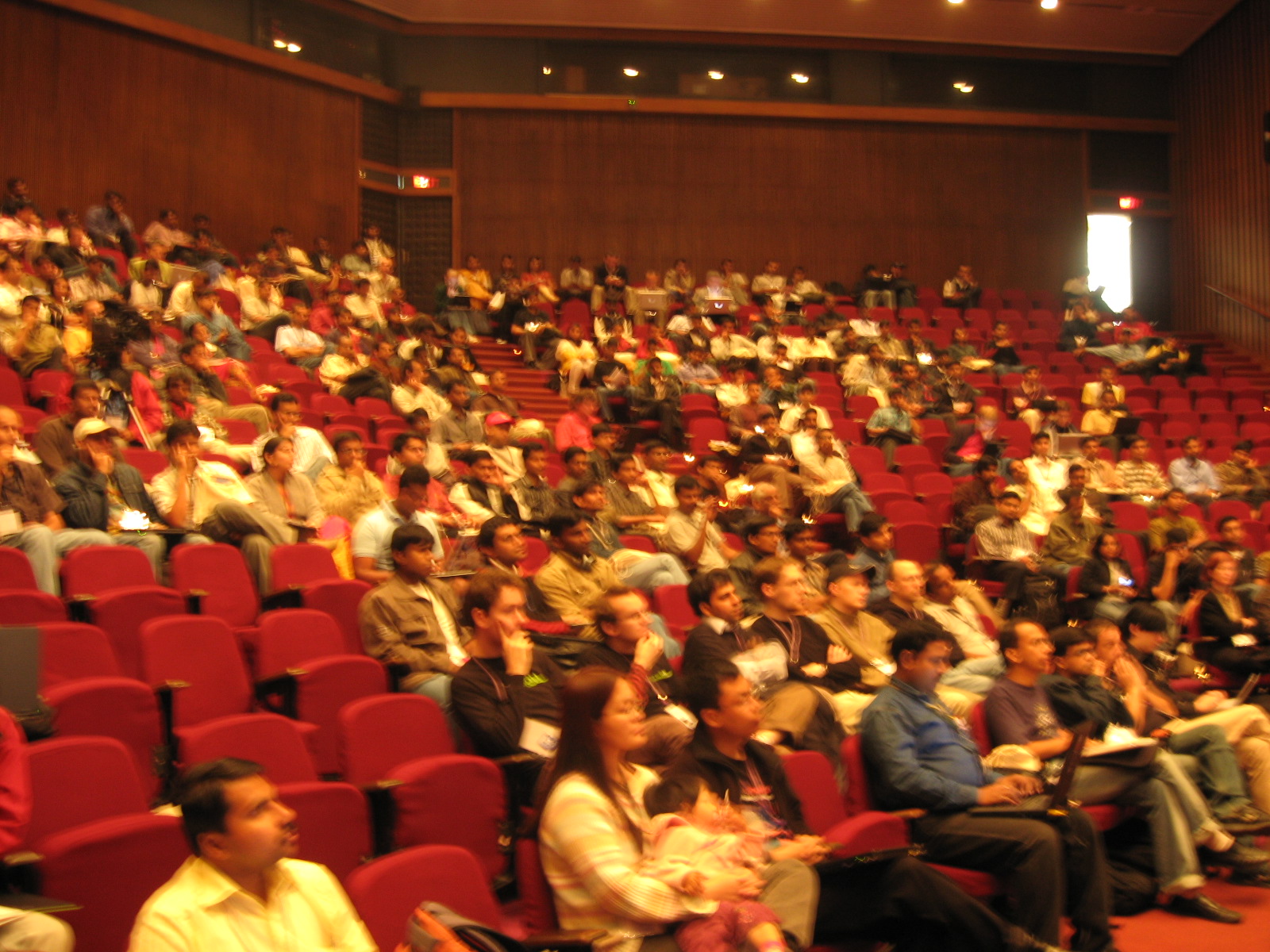many people are in a large auditorium watching soing