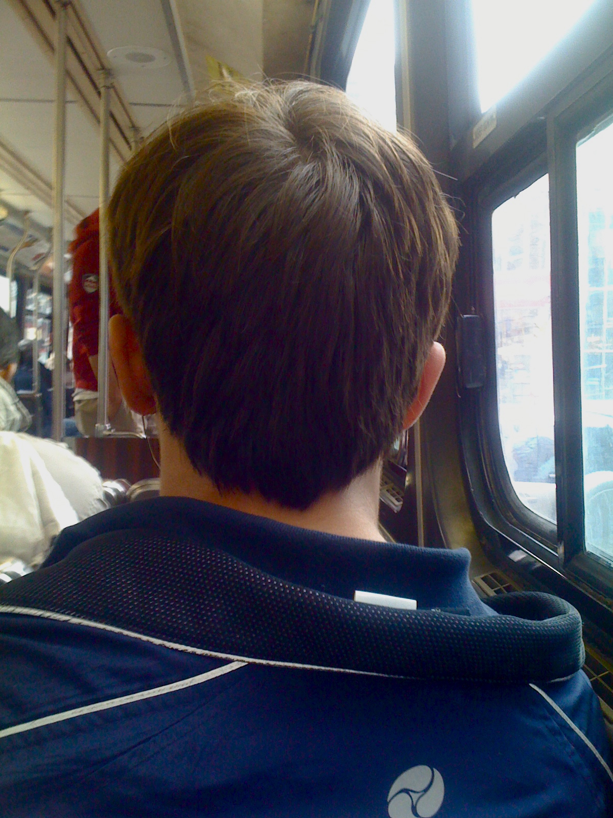 a boy in blue shirt looking out a train window