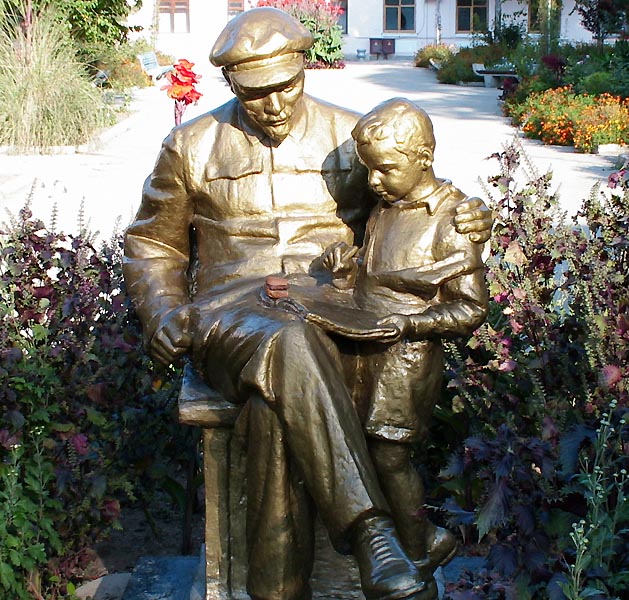 an old bronze statue of a man reading a book