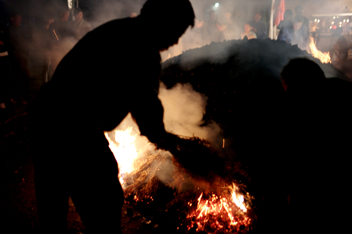 several people standing around a small fire in the dark