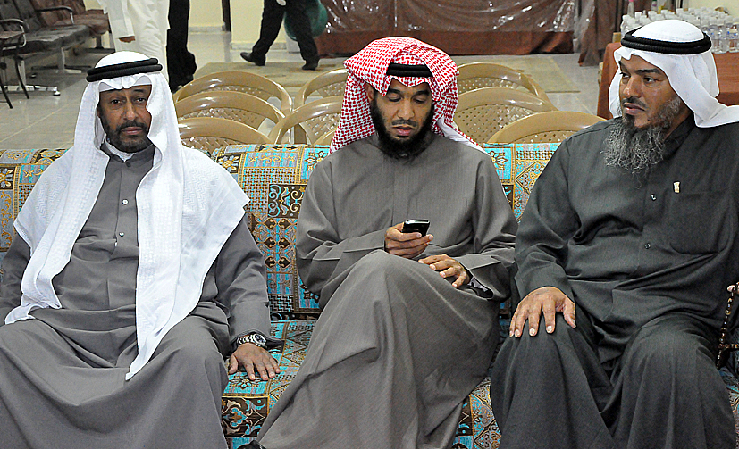 three men in traditional arabic garb are sitting and talking