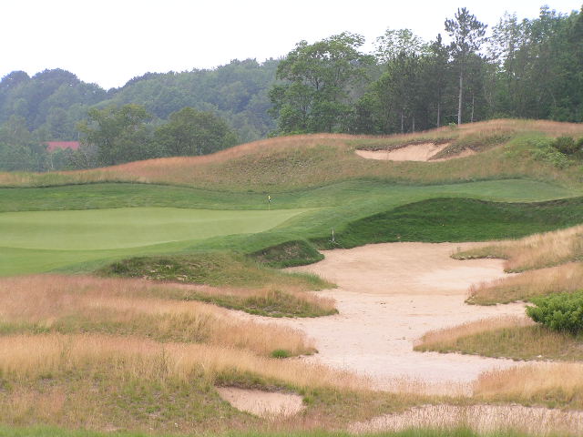 sand bunker holes are in the distance from a golf course