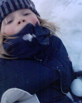 a little girl laying in the snow with her eyes closed