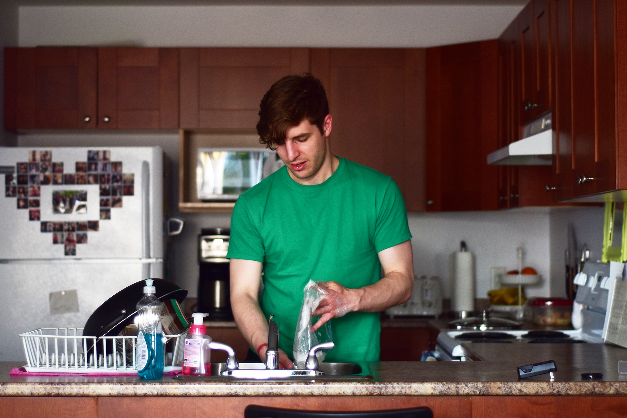 a man in a green shirt making soing in the kitchen