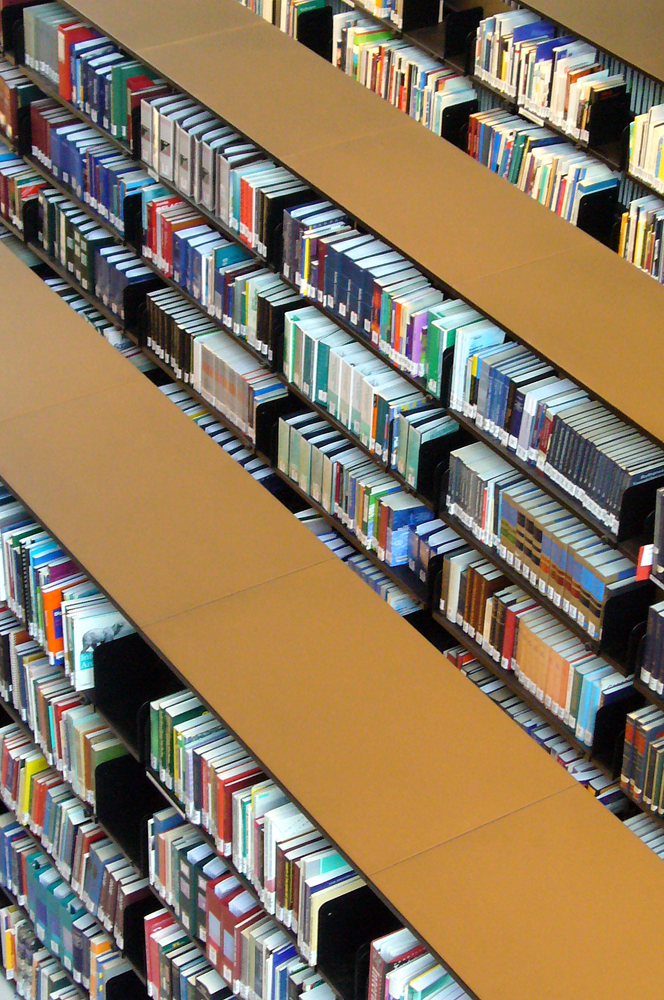 shelves covered in lots of books with a yellow one sitting on the floor