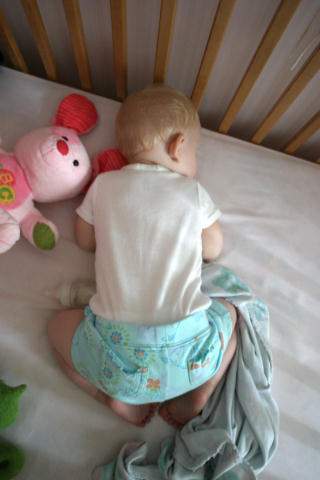 a baby in his diaper sitting next to a teddy bear