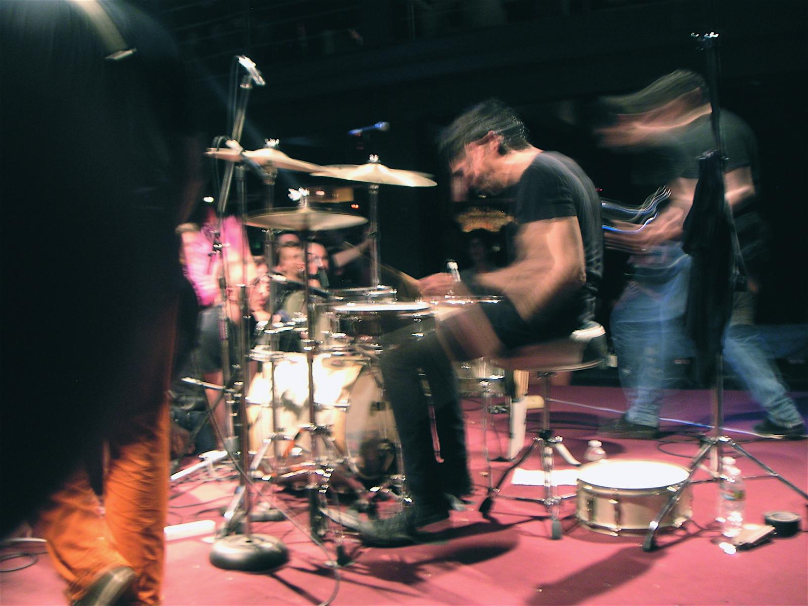 drummer playing drums in front of others at the event