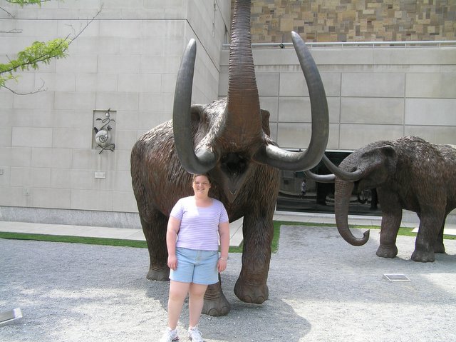 a woman standing next to some statues of elephants