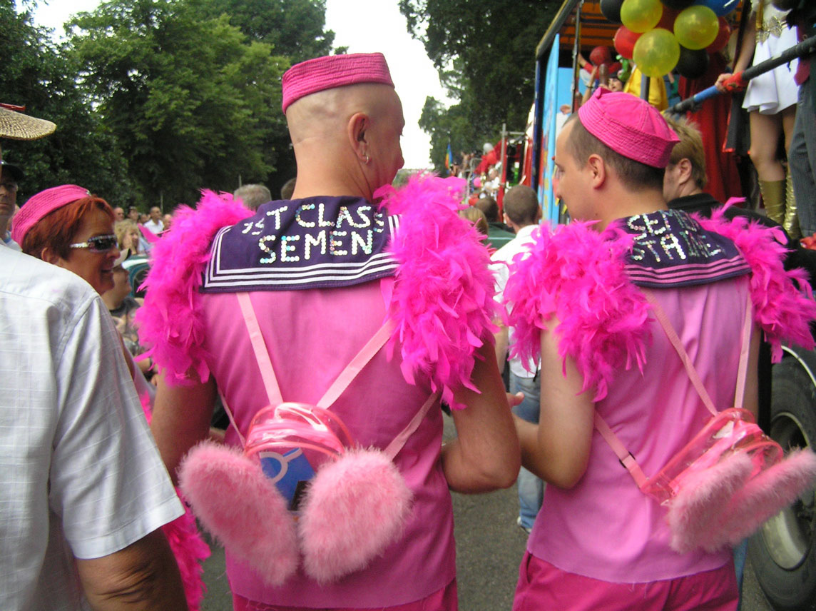 some men are dressed in pink in front of a vehicle